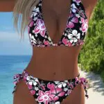Woman in a floral bikini posing by the beach.