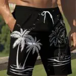 Black swim trunks with white palm tree and island designs.