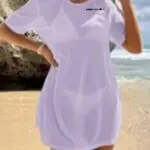 Person wearing a white dress standing on a sandy beach near the ocean.